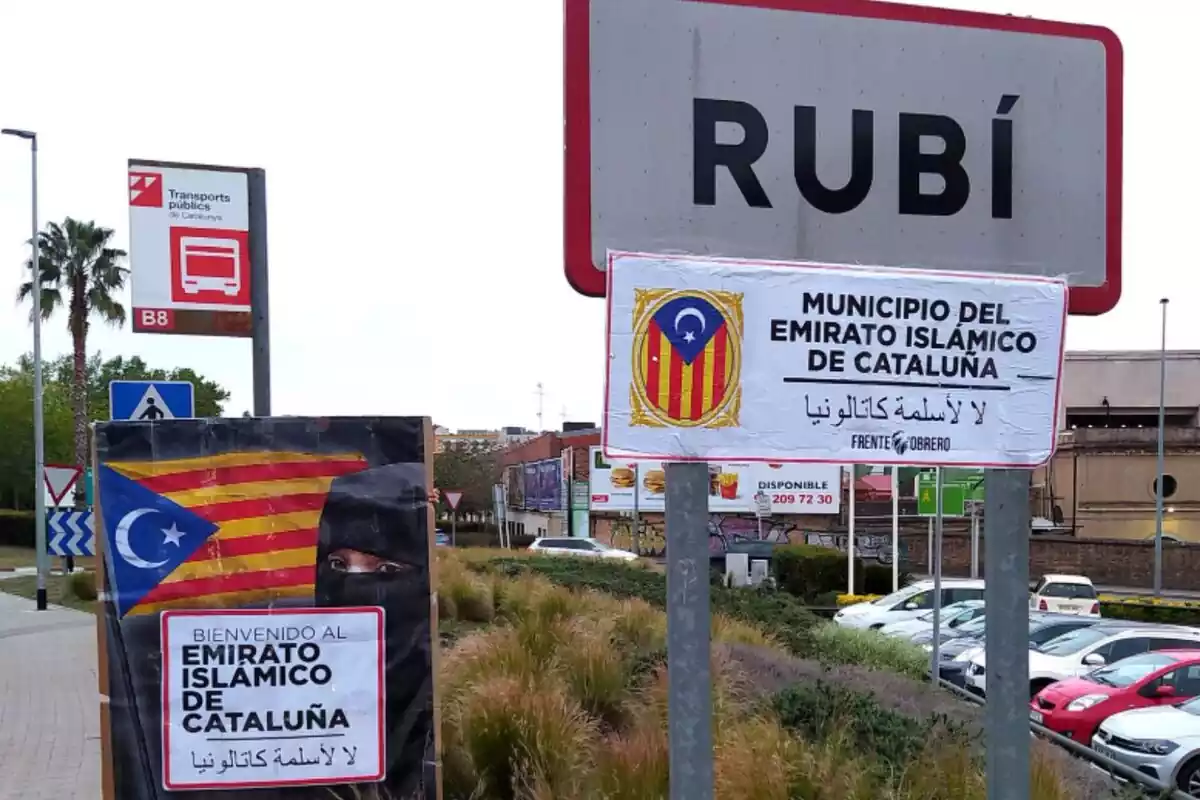 Cartell de l'entrada a Rubí, un poble de Catalunya, amb el nom esborrat i amb cartells que indiquen que és un 'emirat islàmic de Catalunya'