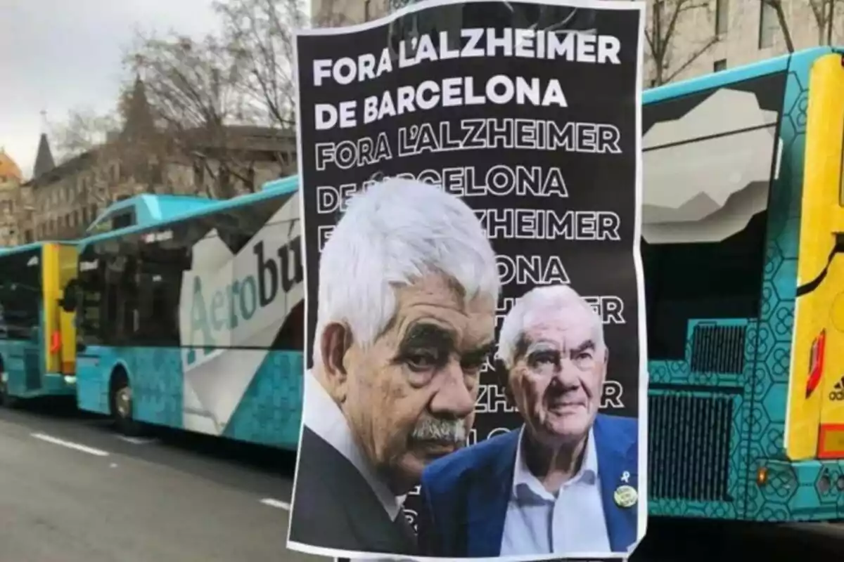 Cartell amb el text "Fora l'Alzheimer de Barcelona" repetit diverses vegades, amb les imatges de Pasqual i Ernes Maragall, enganxat en un pal davant de diversos autobusos en un carrer de la ciutat.