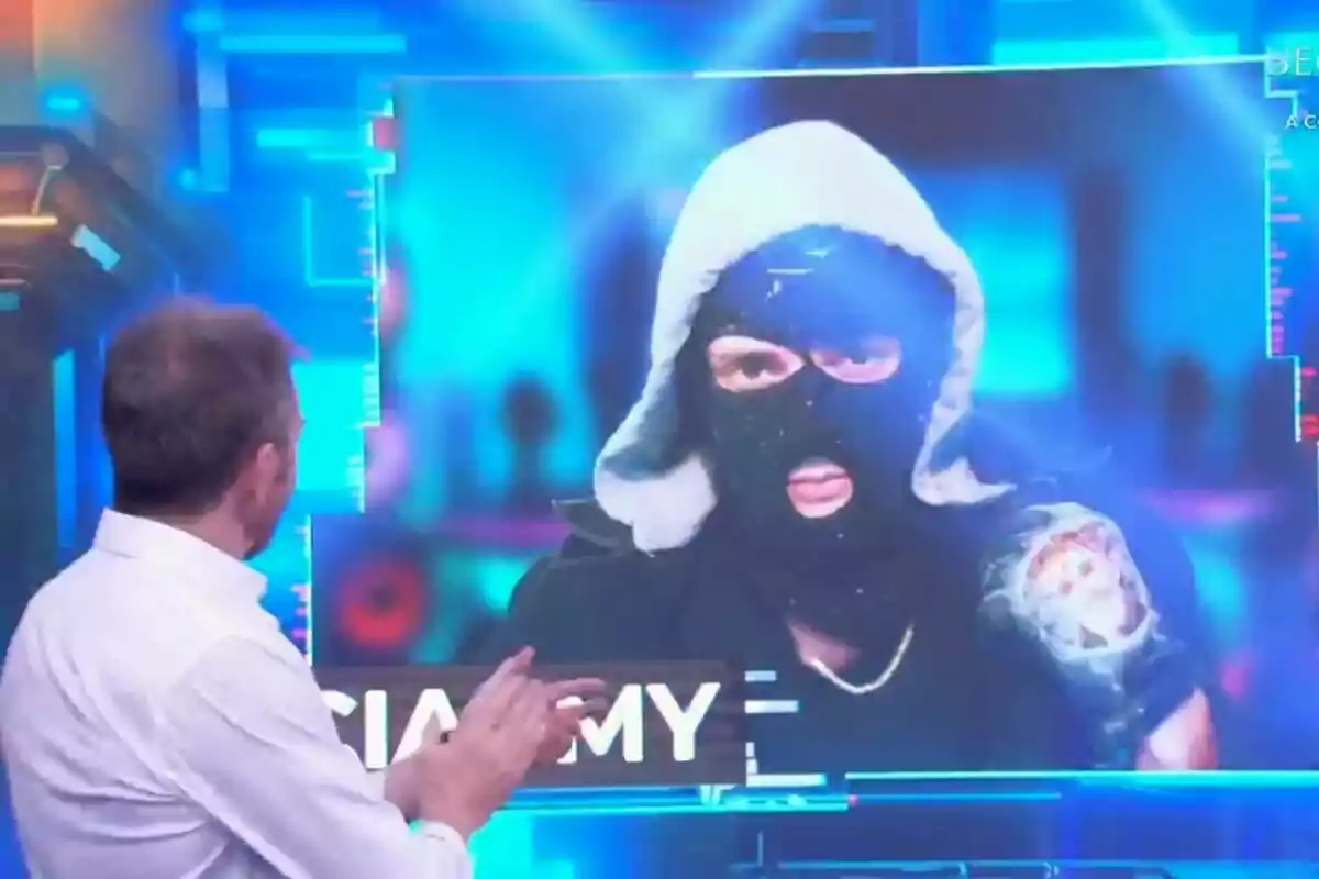 Pablo Motos d'esquena observa una pantalla que mostra Ceciarmy amb passamuntanyes i caputxa a la pantalla del Hormiguero.