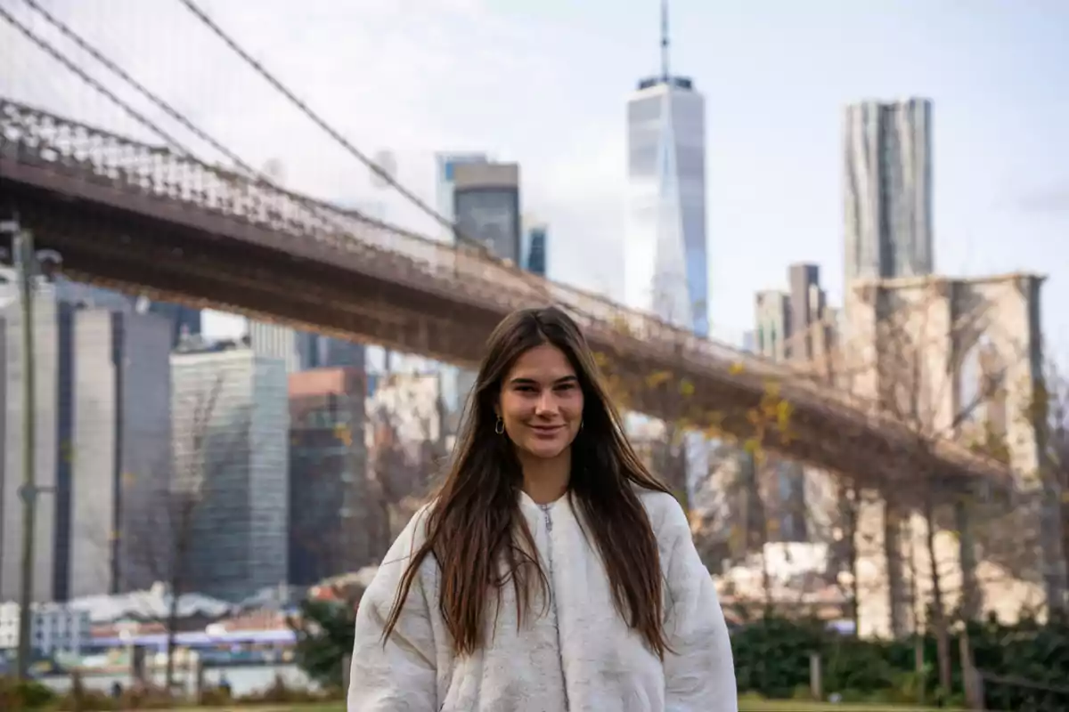 Cèlia Espanya està dreta davant del pont de Brooklyn amb l'skyline de Nova York al fons.