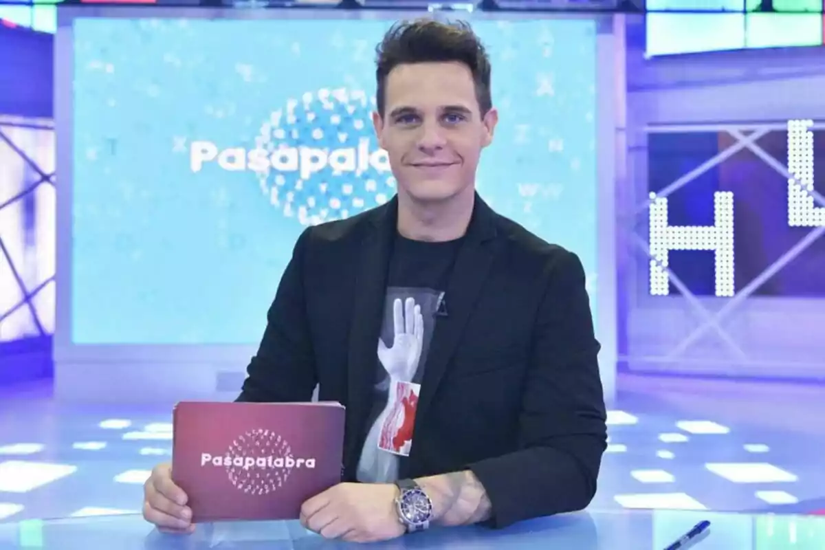 Christian Gálvez com a presentador de televisió sosté una targeta amb el logotip de Christian Gálvez com a presentador de televisió sosté una targeta amb el logotip de