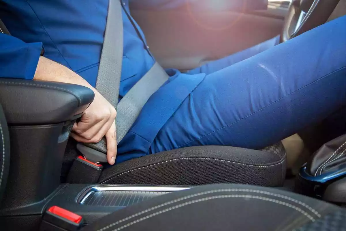 Primer plano de una persona poniéndose el cinturón de seguridad en un coche Primer plano de una persona poniéndose el cinturón de seguridad en un coche