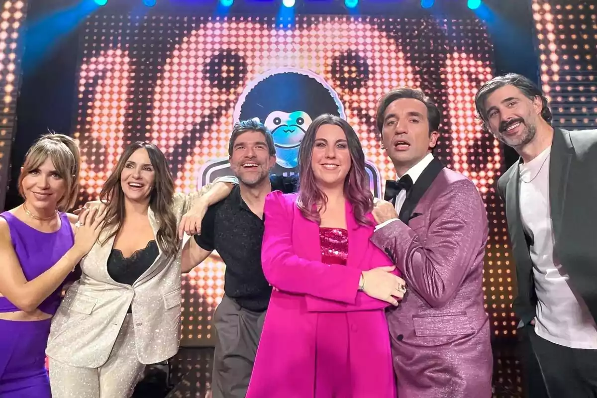 María Gómez, Melani Olivares, Nacho García, Carolina Iglesias, Miguel Lago i David Amor posant juntes en un escenari amb un fons il·luminat i colorit a El Club del Chiste.