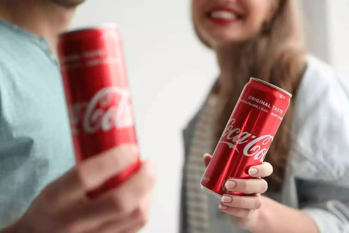 Dos personas sosteniendo una lata de Coca-Cola