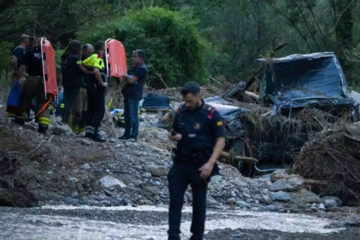 Part del riu amb un cotxe destrossat amb els Mossos d'Esquadra i els bombers