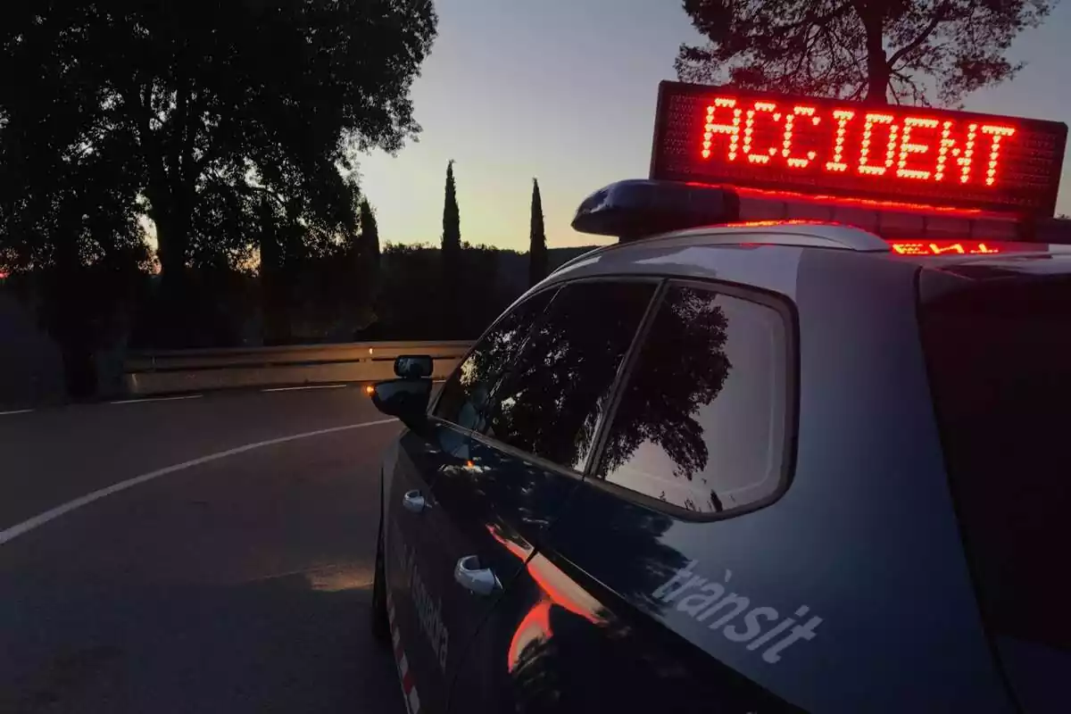 Plànol curt d'un cotxe dels Mossos d'Esquadra que té el cartell d''Accident' enmig d'una carretera