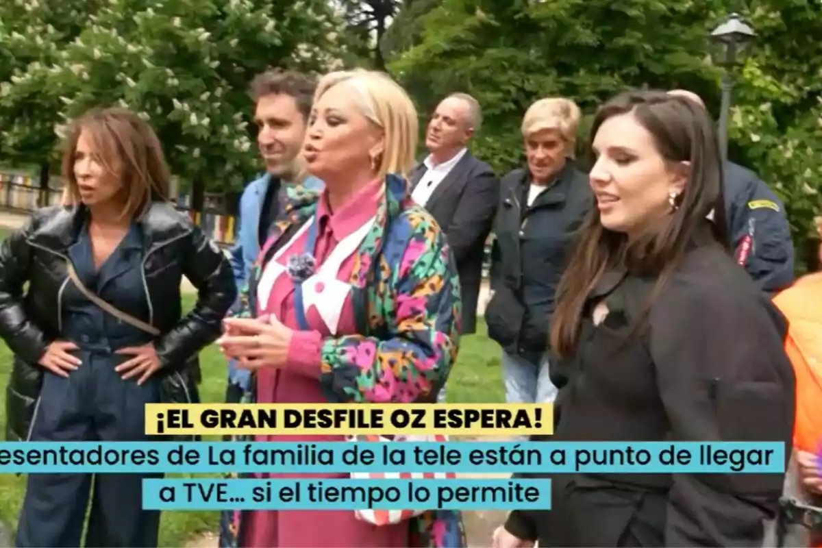 Un grup de persones format per Belén Esteban, María Patiño, Aitor Albizua, Inés Hernand, Víctor Sandoval, Chelo García Cortés i Kiko Matamoros està reunit a l'aire lliure, algunes d'elles conversen mentre altres observen, i hi ha un cartell que menciona una desfilada a La Família de la Tele.