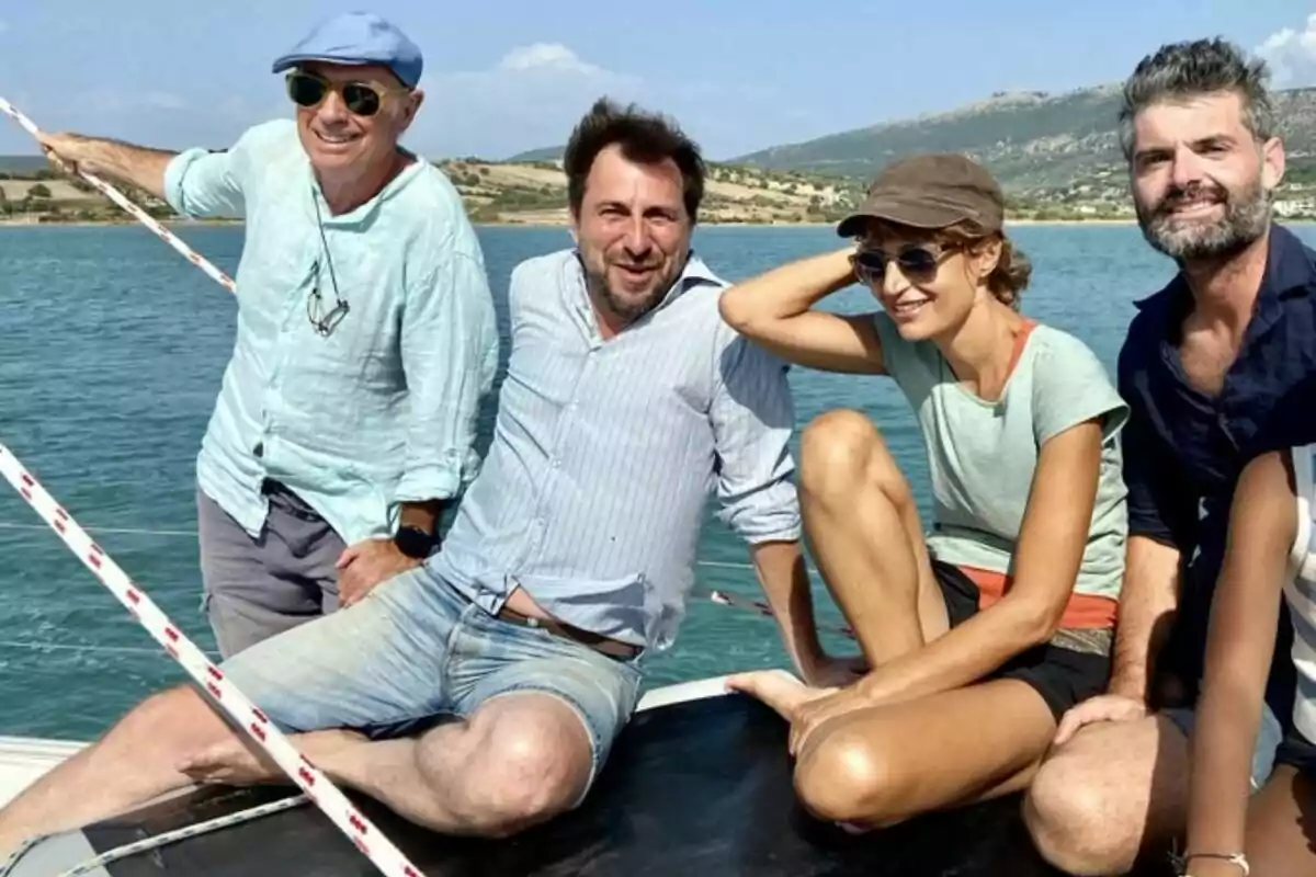 Un grupo de personas sonríe mientras disfruta de un día soleado en un bote sobre el agua con un paisaje montañoso al fondo.