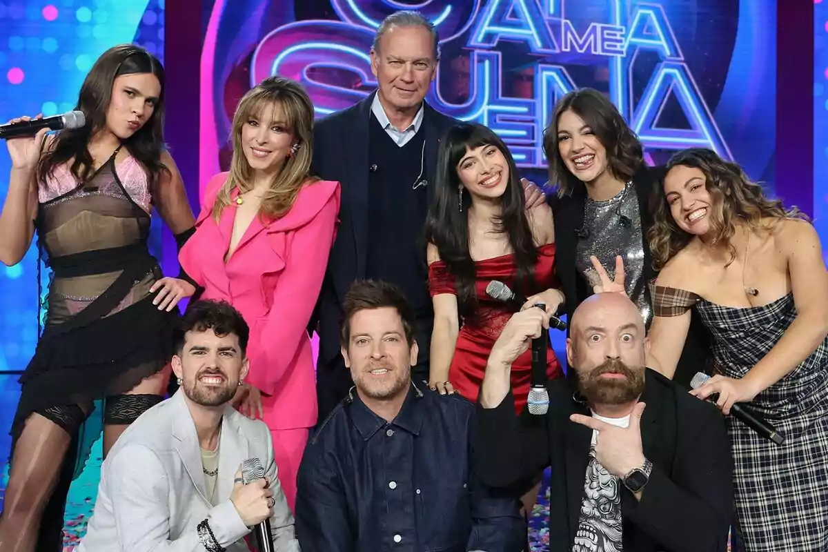 Un grupo de personas formado por Bertín Osborne, Ana Guerra, Manu Baqueiro, Gisela, Goyo Jiménez, Yenesi, Esperansa Grasia, Melani García y Mikel Herzog Jr. posando juntas en el plató de Tu Cara Me Suena, algunas sosteniendo micrófonos y sonriendo a la cámara, con un fondo colorido y un letrero que parece ser parte del programa.