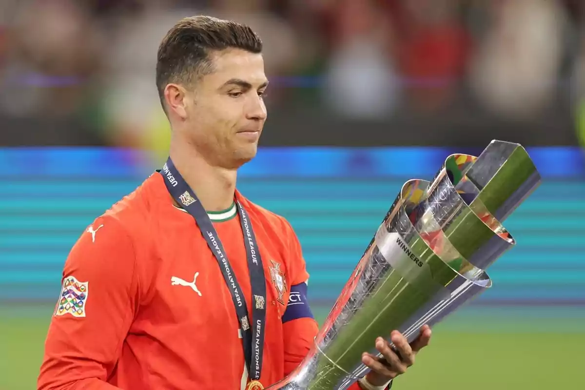 Soccer player in a red uniform holding a silver trophy at an award ceremony Soccer player in a red uniform holding a silver trophy at an award ceremony