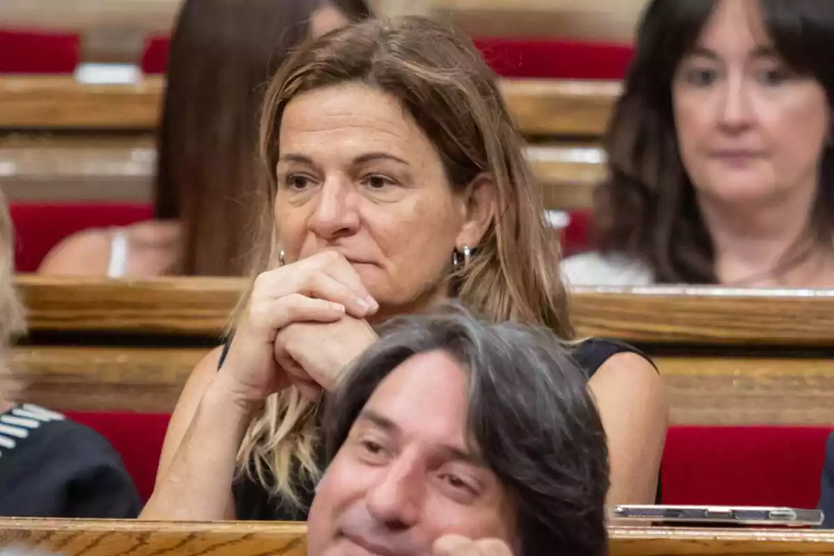 Cristina Casol, asseguda al seu escó al Parlament de Catalunya, amb els colzes recolzats a la taula i els seus punys, junts, entre la barbeta i la boca