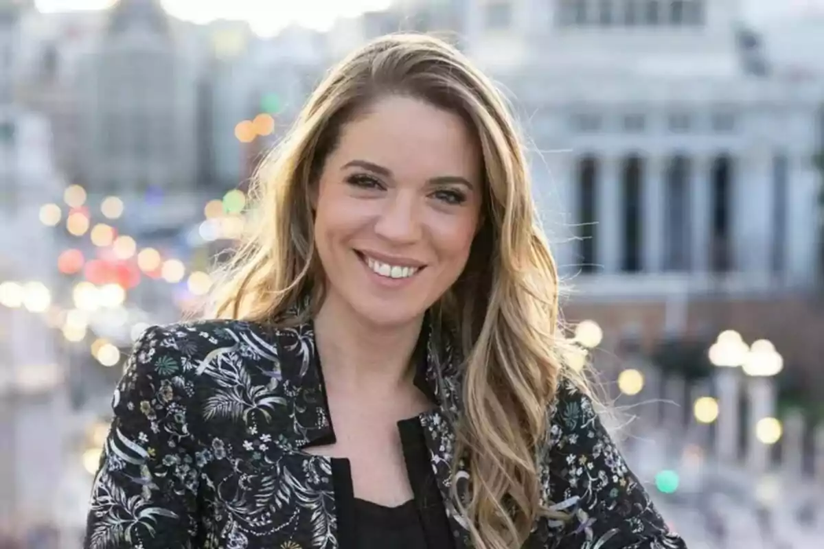 Cristina Lasvignes, jove de cabell ros i llarg somrient a l’aire lliure amb un fons urbà desenfocat i llums de la ciutat al capvespre. Cristina Lasvignes, jove de cabell ros i llarg somrient a l’aire lliure amb un fons urbà desenfocat i llums de la ciutat al capvespre.