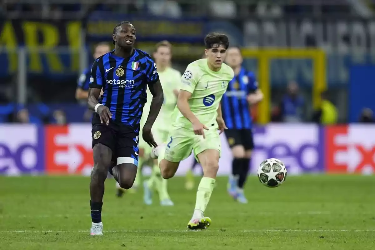 Jugadors de futbol corren darrere la pilota en un partit, un porta uniforme blau i negre i l'altre verd clar. Jugadors de futbol corren darrere la pilota en un partit, un porta uniforme blau i negre i l'altre verd clar.