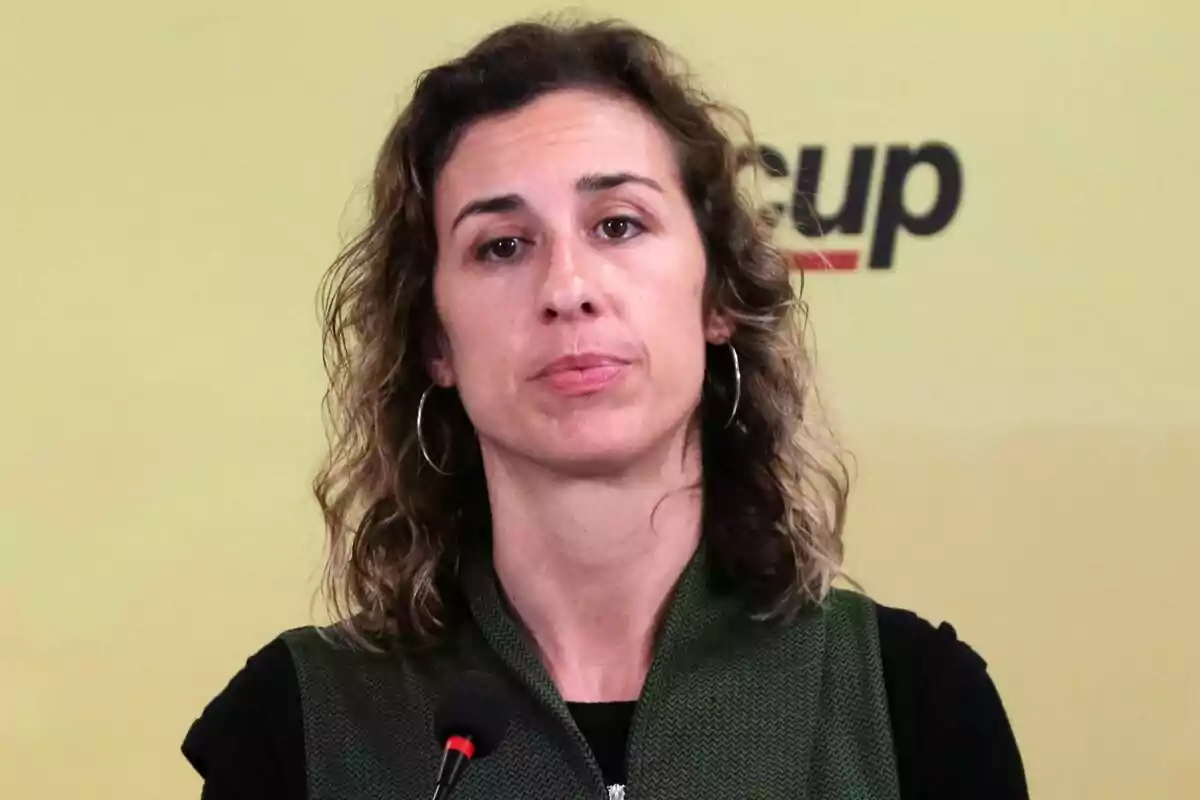 Laia Estrada parlant davant d'un micròfon amb un fons groc i el logotip de "cup" parcialment visible.