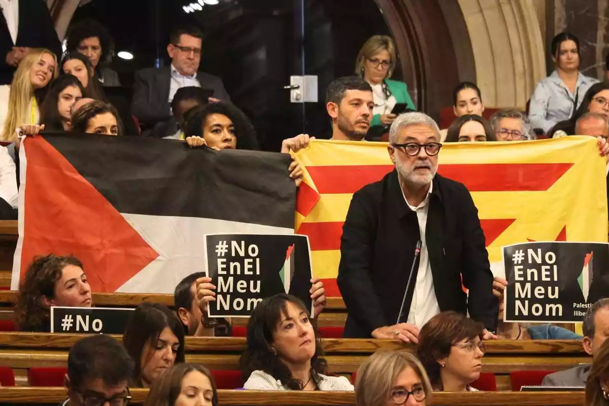 Carles Riera de la CUP intervenint al Parlament amb altres diputats de la CUP per darrere mostrant una bandera estelada i una altra de Palestina