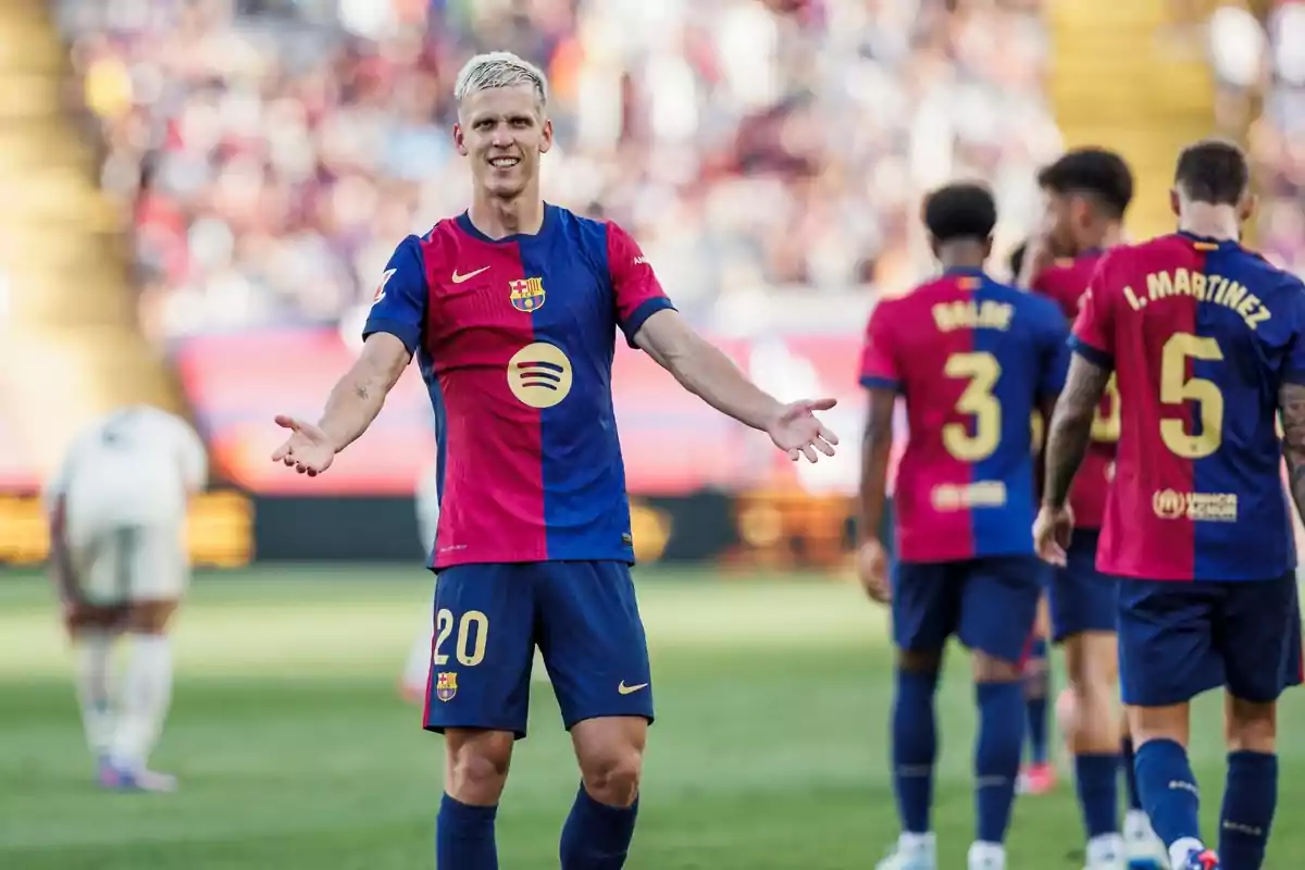 An FC Barcelona player with the number 20 on his shirt stands on the football field with his arms outstretched, while other players with the numbers 3 and 5 have their backs turned.