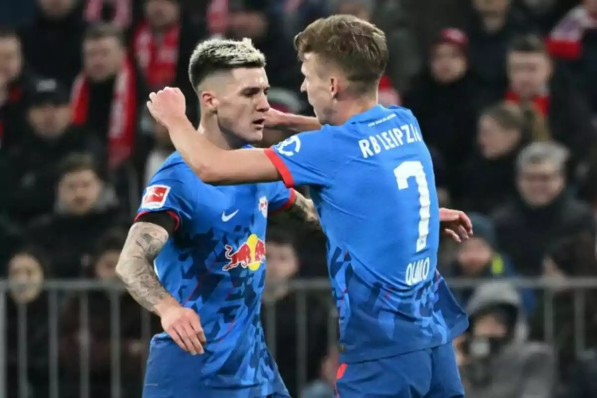 Dos jugadores de fútbol del RB Leipzig celebran un gol en el campo. Dos jugadores de fútbol del RB Leipzig celebran un gol en el campo.