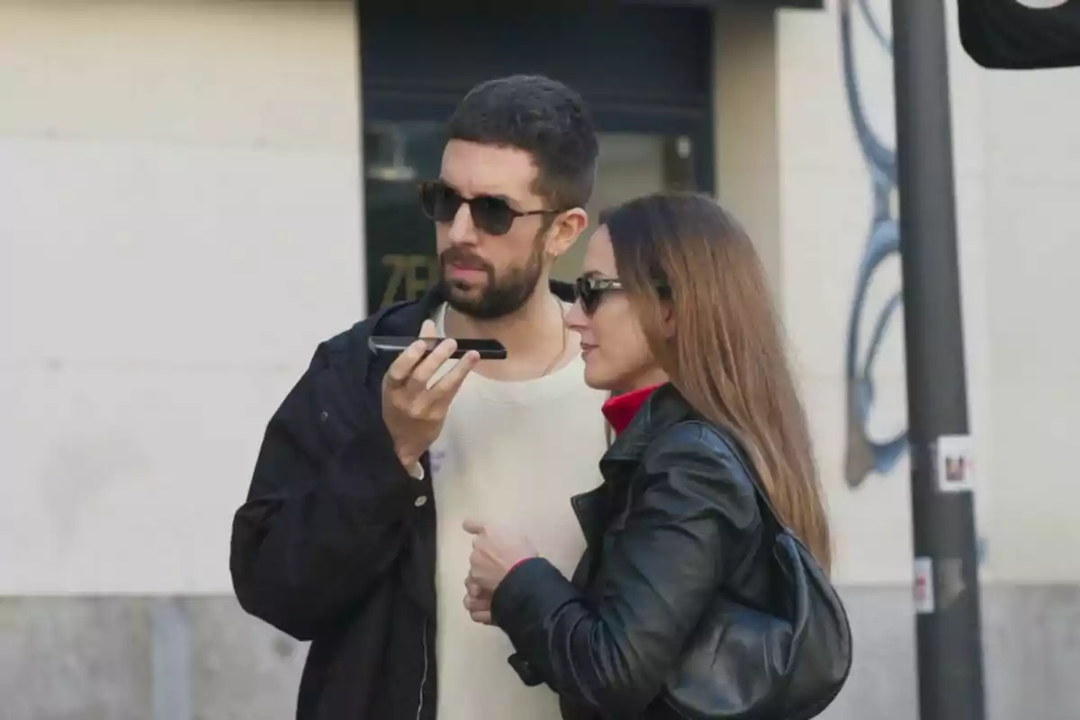 Fotografía de David Broncano con una mujer con gafas de sol mirando un teléfono móvil en la calle en Medina: El estafador de famosos