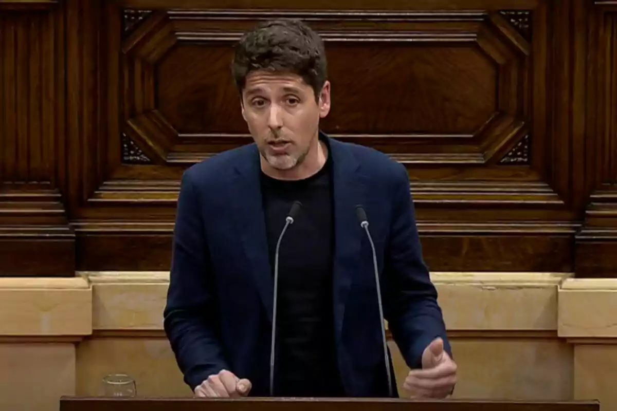 Un home parlant en un faristol amb un fons de fusta decorativa. Un home parlant en un faristol amb un fons de fusta decorativa.