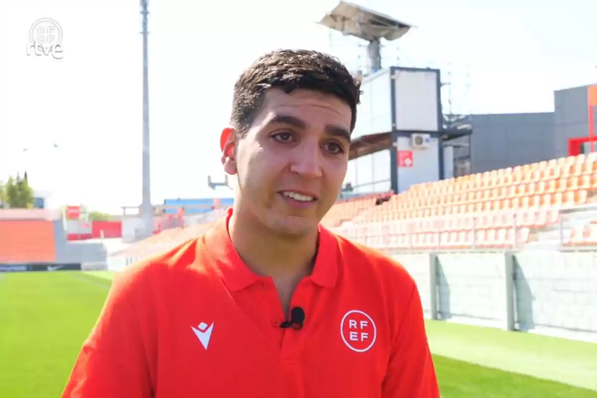 David García amb samarreta vermella de la RFEF és en un estadi de futbol.