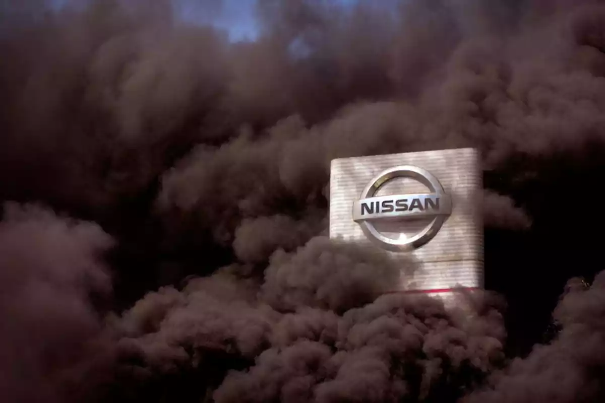 un cel blau tapat per fum marró molt espès i enmig un edifici blanc amb el logo de Nissan