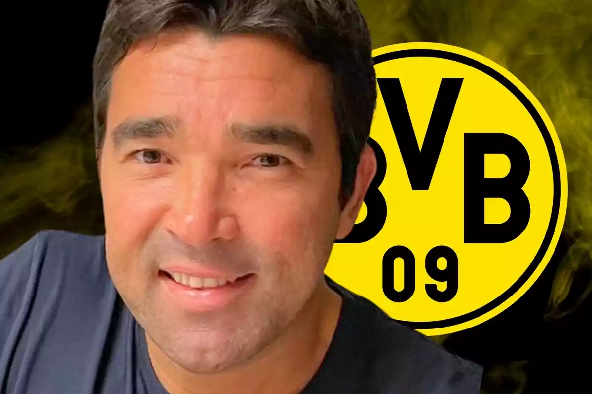 A smiling man with dark hair in front of a background with the Borussia Dortmund logo.