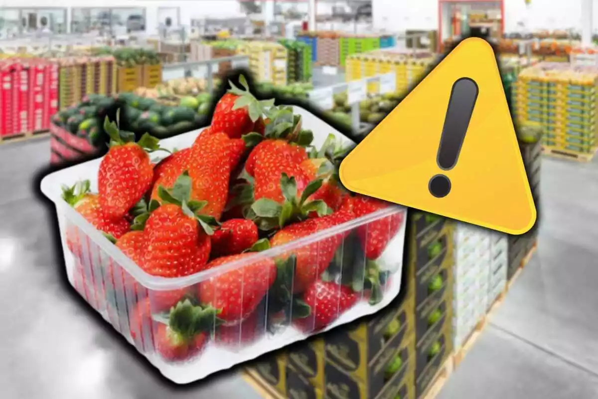 Muntatge amb triangle d'alerta a la cantonada superior esquerra i una caixa de maduixes al centre sobre fons de magatzem de fruites supermercat desenfocat