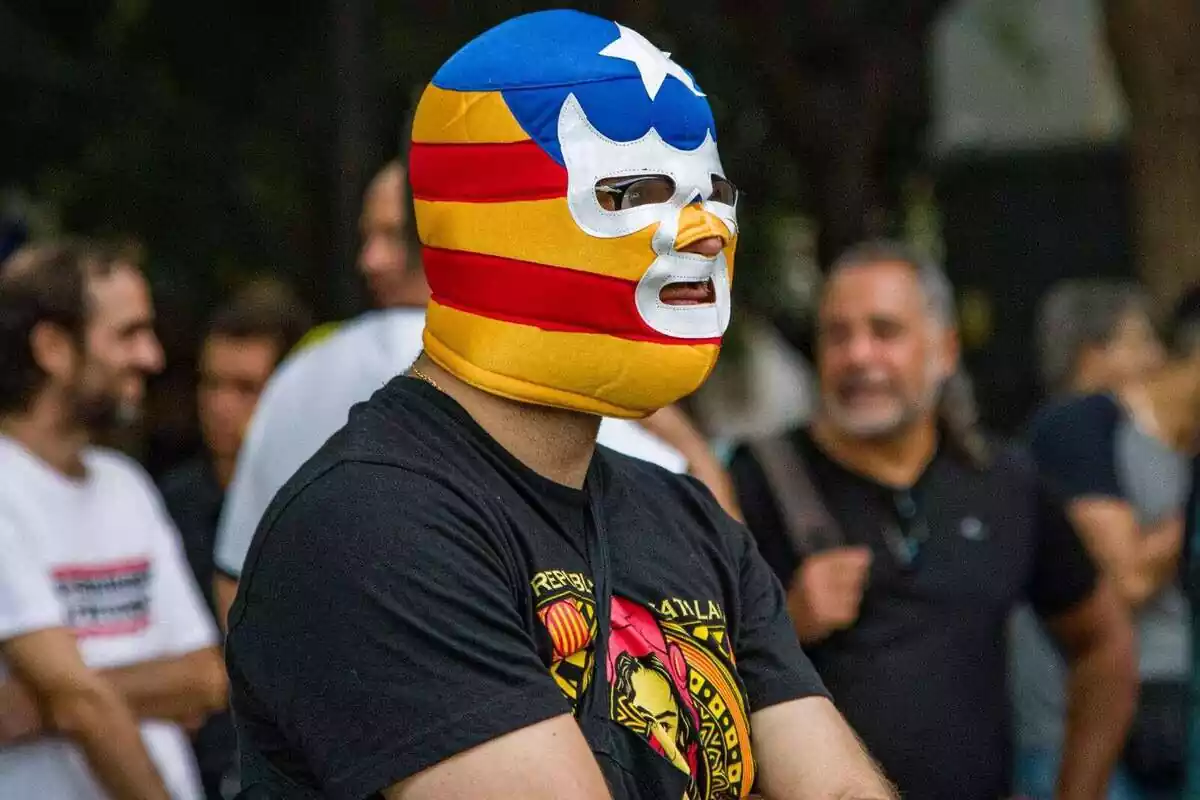 Pla mitjà d'un manifestant independentista amb una màscara estil lluitador mexicà amb els colors de la bandera estelada