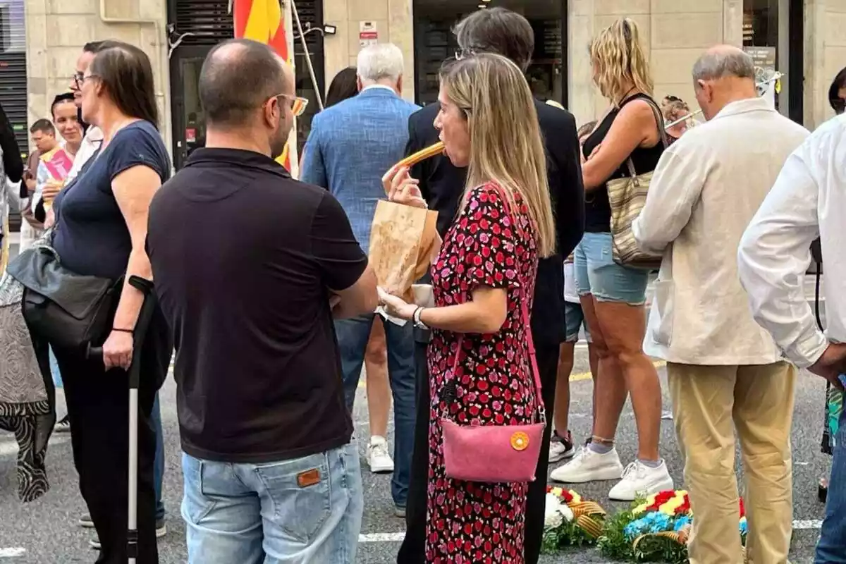 Pla americà duna parella. La dona, de perfil, amb un vestit de roses es menja un xurro. L'home, d'esquena, amb un pol negre i texans