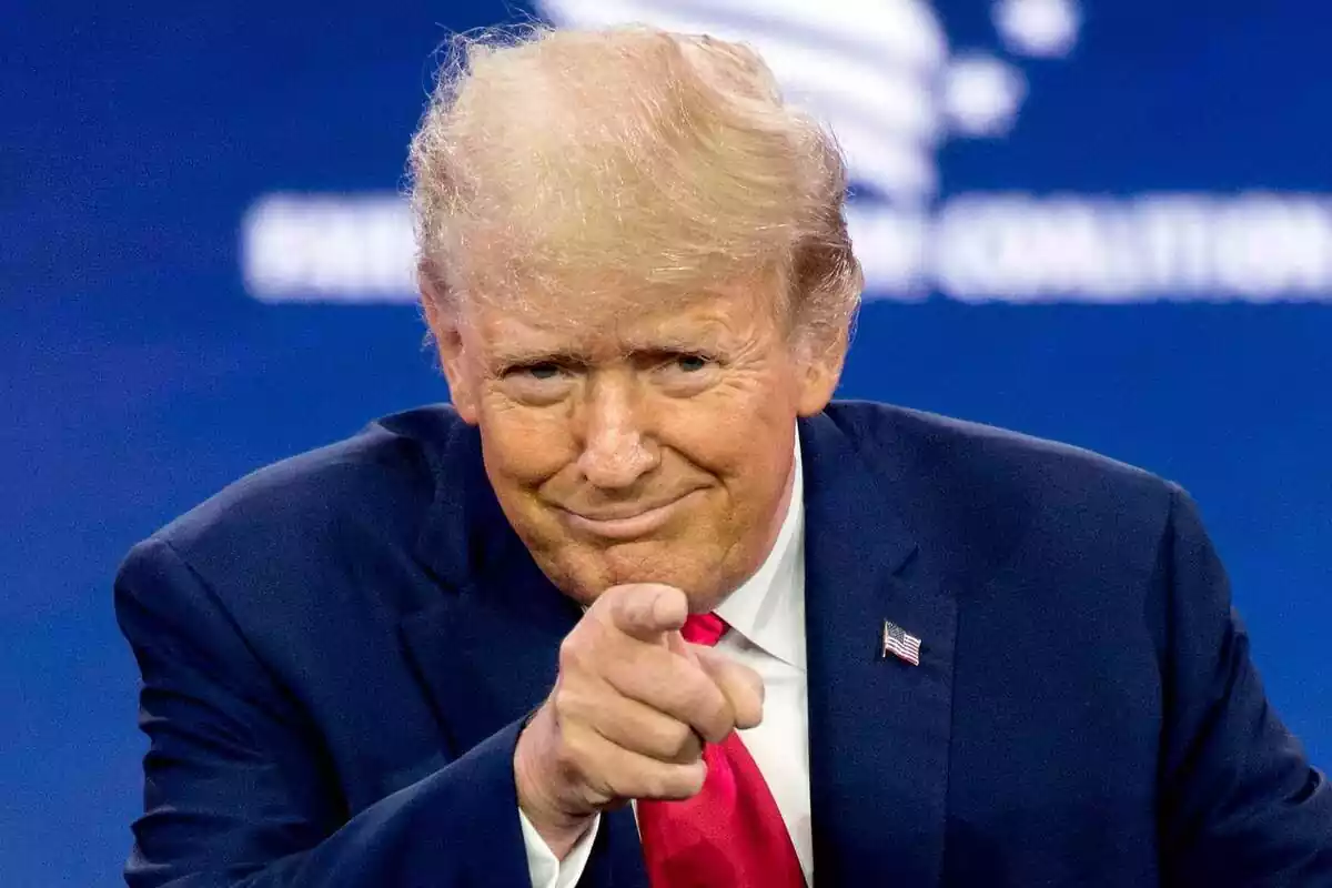 Pla mitjà curt de Donald Trump somrient i assenyalant al capdavant amb el seu dit índex