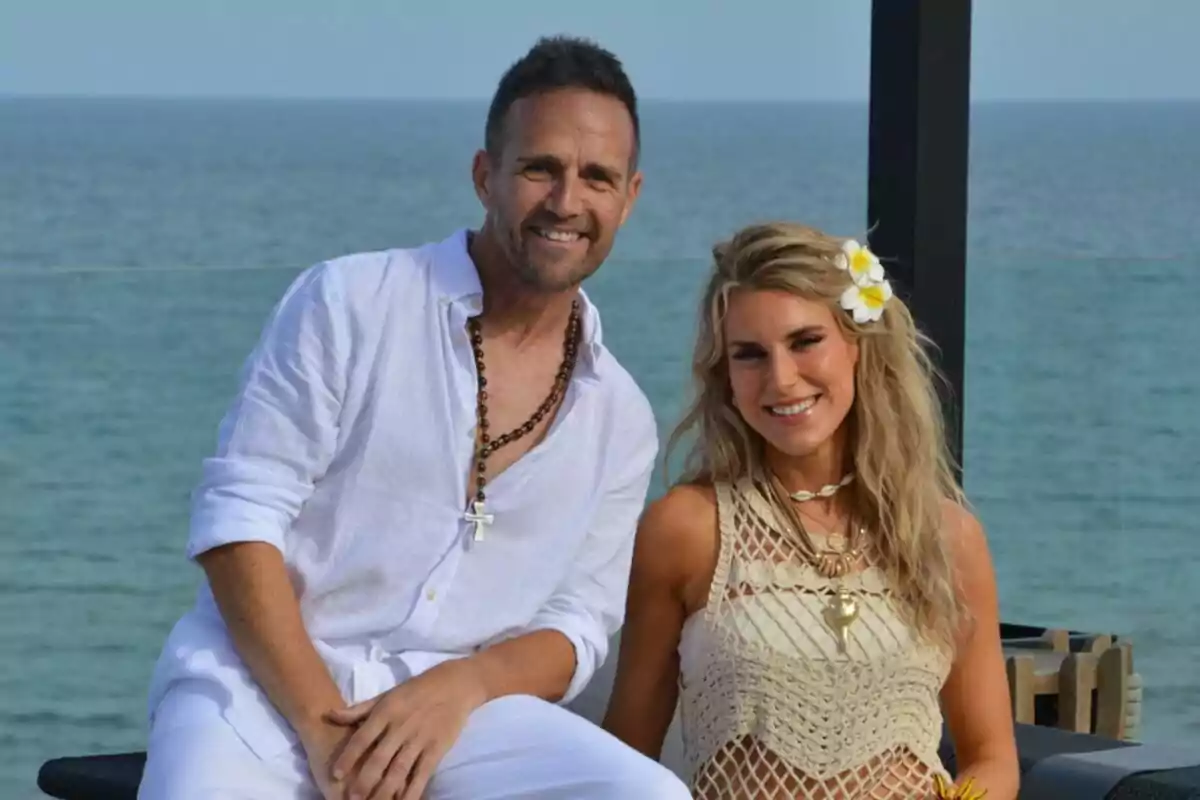 Eduard Forés i María Fuster somrient vestida de blanc i beix posant davant del mar en un ambient relaxat i estiuenc Eduard Forés i María Fuster somrient vestida de blanc i beix posant davant del mar en un ambient relaxat i estiuenc