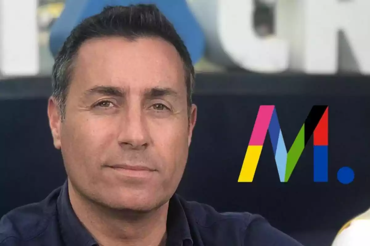 Eduardo Blanco de cabell curt i fosc amb camisa blava, al fons un logotip colorit de Mediaset amb la lletra M i un punt blau