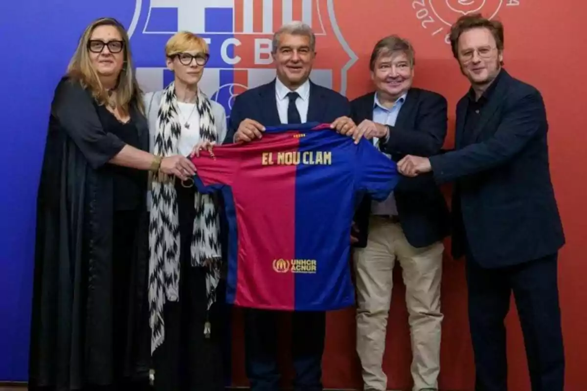 Elena Fort, Rosa Romà, Joan Laporta, Sigfrid Gras i David Carabén sostenint una samarreta del FC Barcelona amb el text “El Nou Clam” davant d'un fons amb el logo del club.