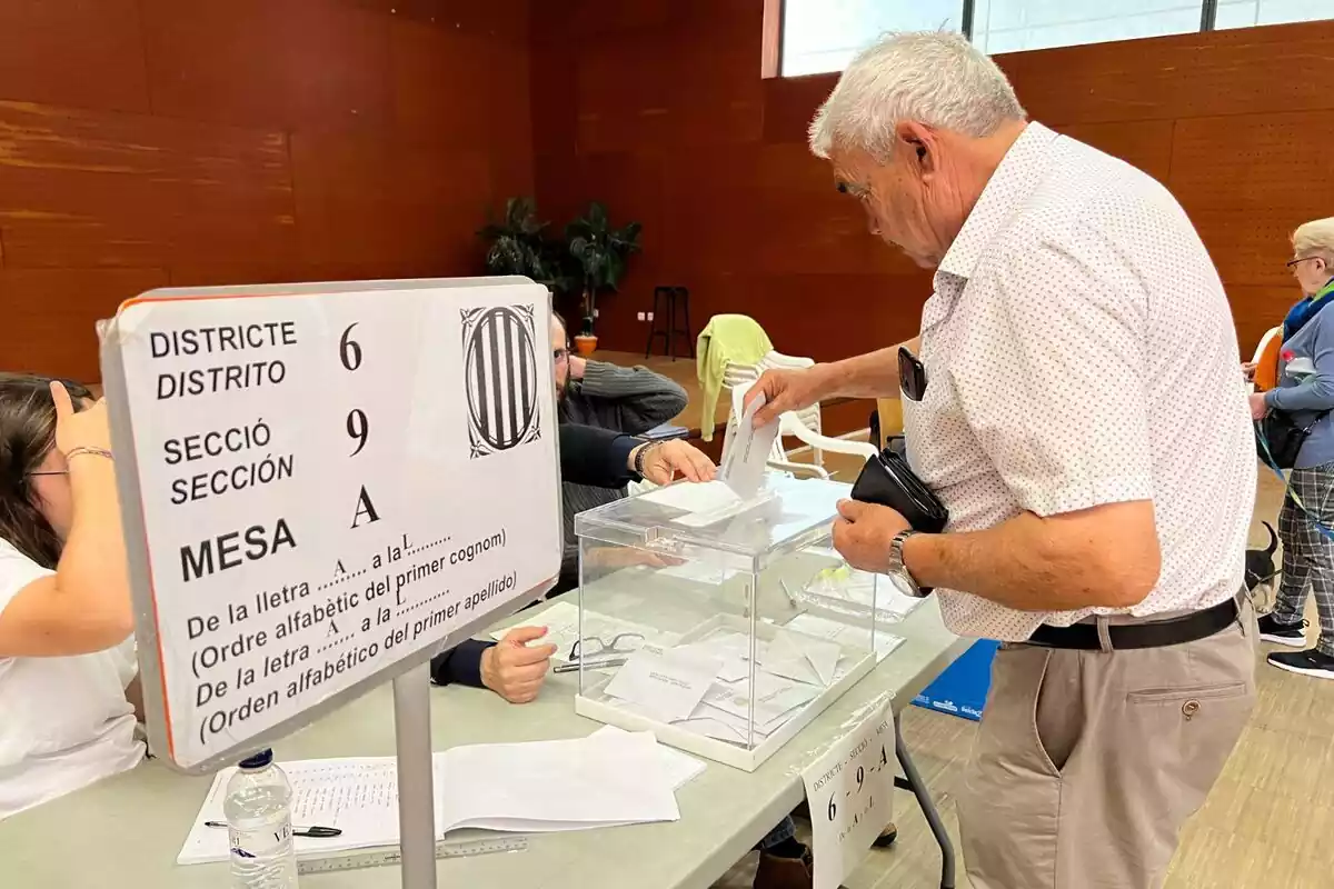 Pla americà d'un senyor gran introduint el vot en una urna d'una mesa electoral a Catalunya