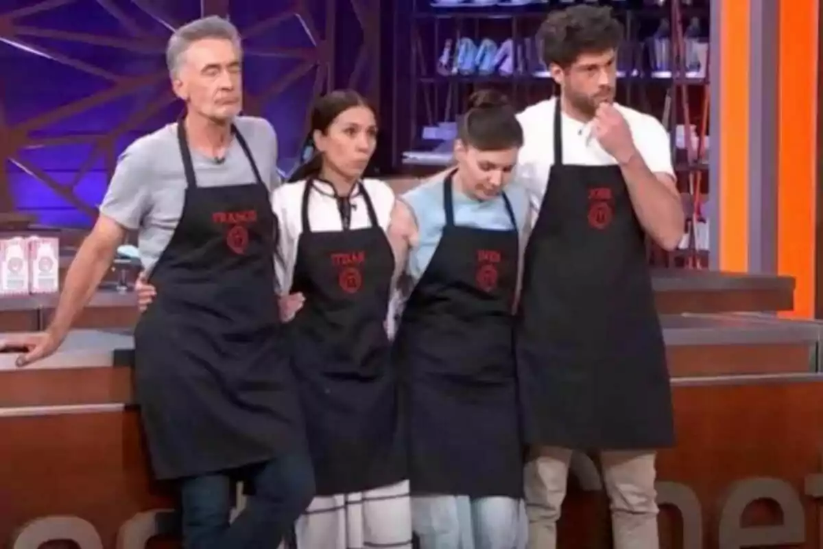 Francis Lorenzo, Itziar Miranda, Inés Hernand i José Lamuño amb davantals negres i noms brodats en vermell estan drets en un set de cuina a MasterChef Celebrity.