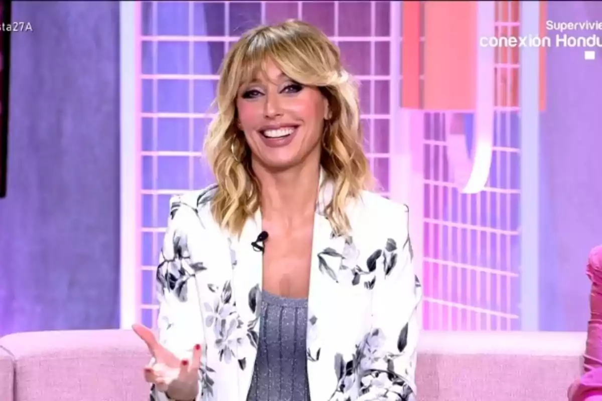 Emma García, somrient amb cabell ros i ondulat, porta un blazer amb estampat floral al plató de 'Festa'. Emma García, somrient amb cabell ros i ondulat, porta un blazer amb estampat floral al plató de 'Festa'.