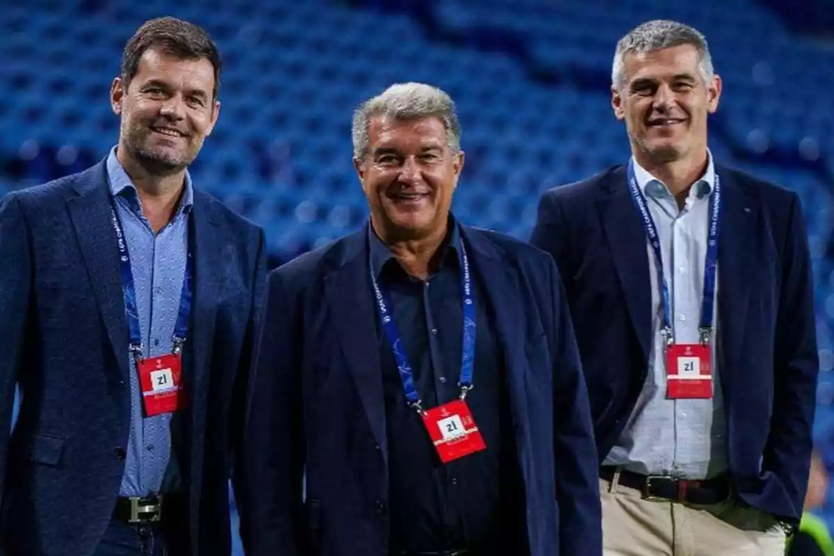 Pla mitjà de Joan Laporta, Enric Masip i un altre directiu del FC Barcelona somrient en un estadi amb seients blaus de fons