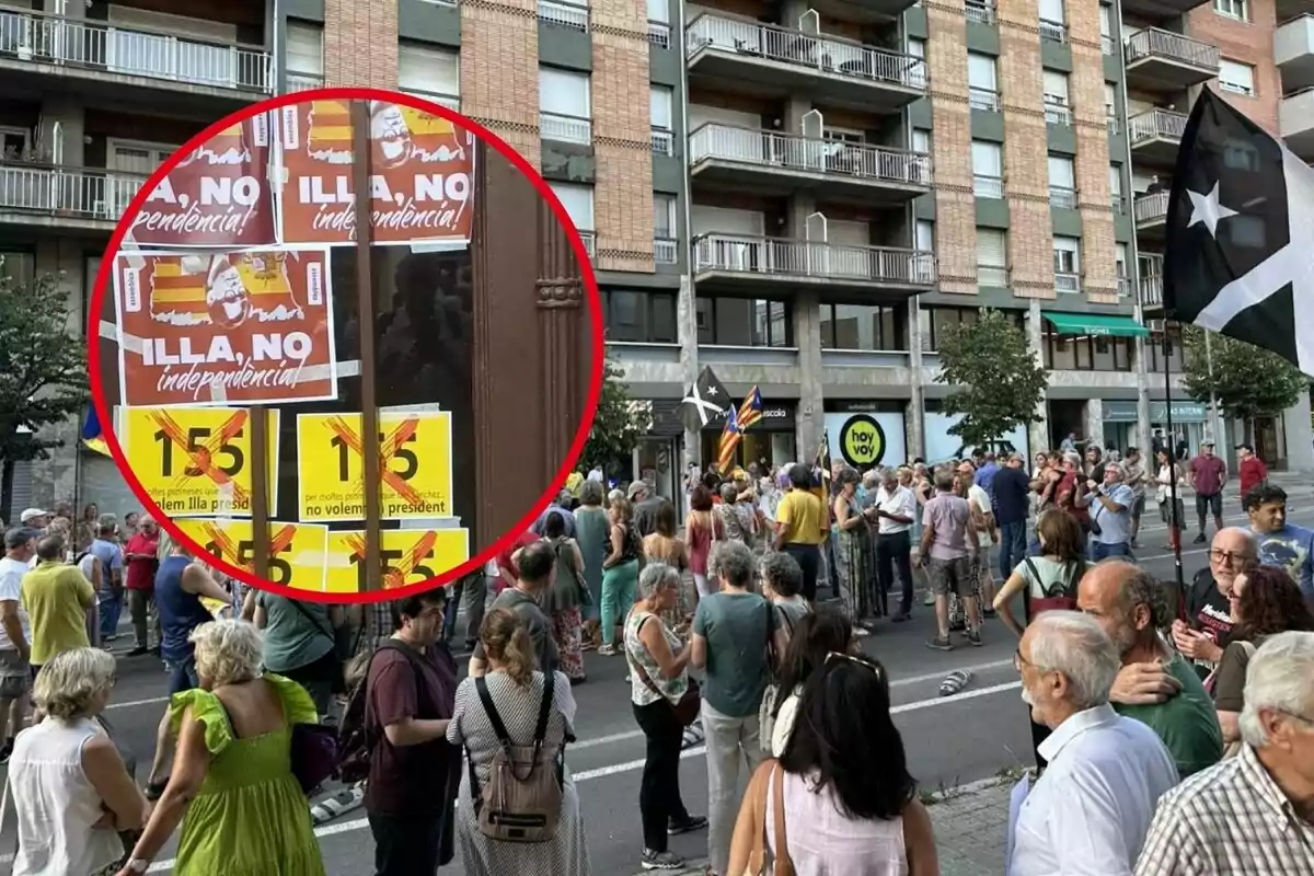 Una multitud de persones s'ha reunit en un carrer, amb cartells i banderes que expressen missatges polítics, destacant-ne un que diu "ILLA, NO independència" i altres que rebutgen l'article 155.