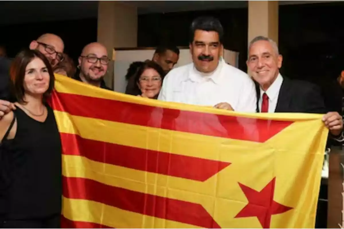 Un grup de persones sostenint una bandera amb franges vermelles i grogues i una estrella vermella.