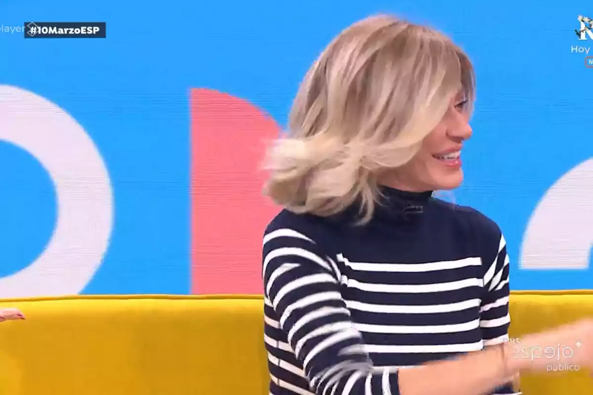 Susanna Griso, wearing a striped sweater, sitting on a yellow sofa with a blue and red background. Capture from 'Espejo Público'. Susanna Griso, wearing a striped sweater, sitting on a yellow sofa with a blue and red background. Capture from 'Espejo Público'.