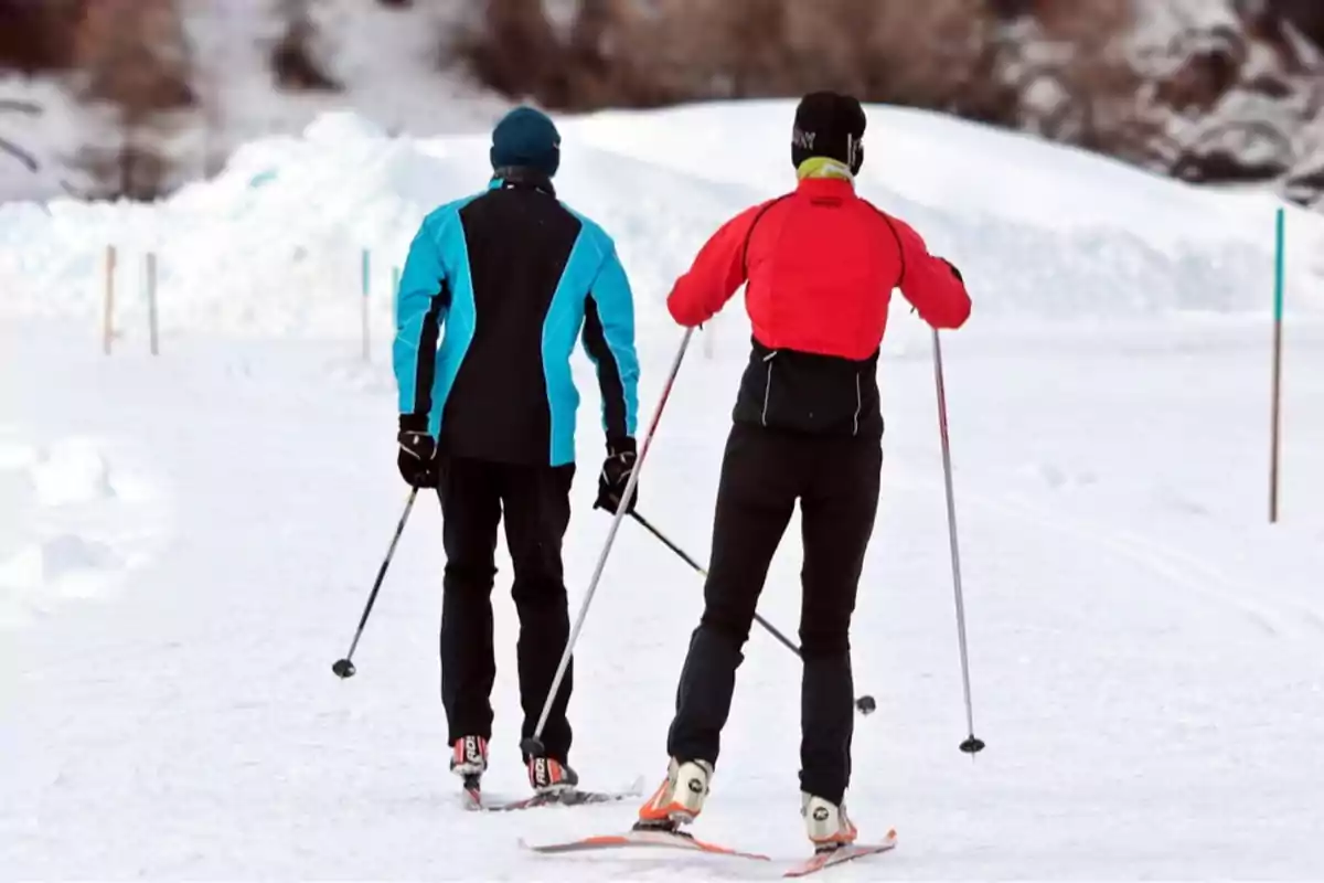 Dos personas esquiando en la nieve con ropa de invierno.