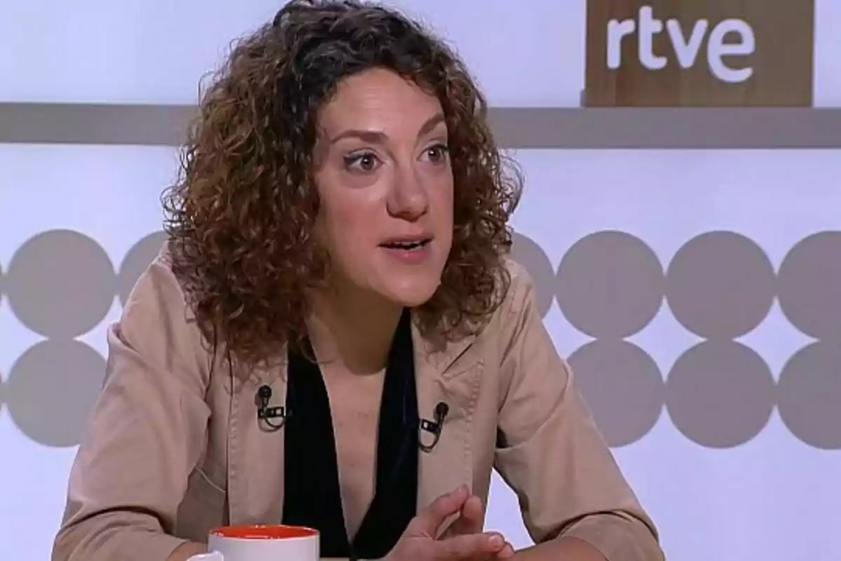 Dona de cabell arrissat parlant en un programa de televisió amb el logotip de RTVE al fons.