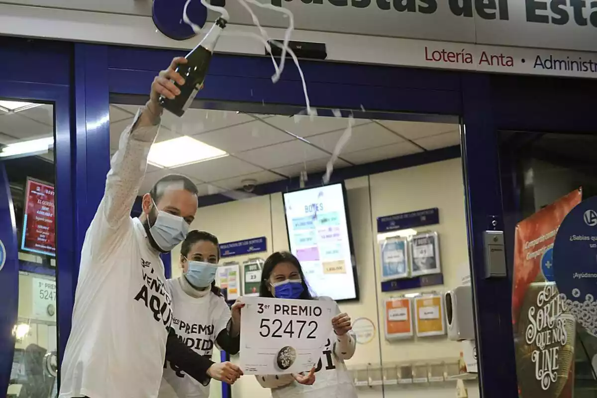 Tres persones celebrant amb una ampolla de cava que els ha tocat el tercer premi de la Loteria