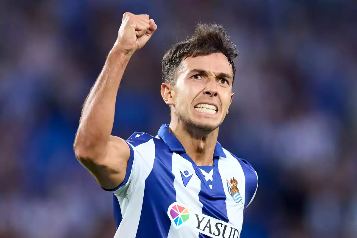 Jugador de futbol celebrant amb el puny enlaire mentre vesteix l'uniforme de la Reial Societat.