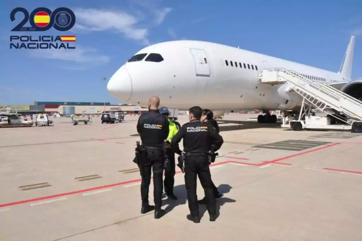 Policies nacionals d?Espanya en un aeroport al costat d?un avió blanc.