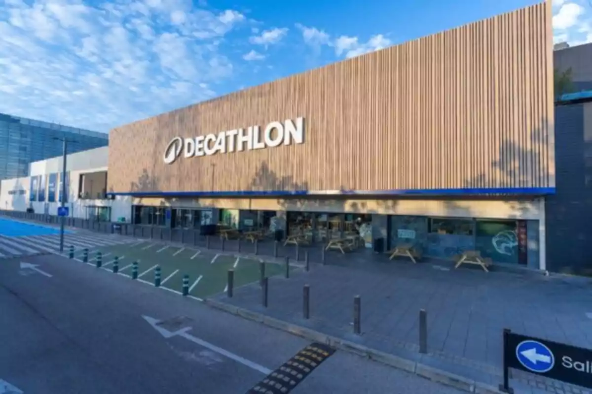Fachada de una tienda Decathlon con un cielo despejado y un área de estacionamiento en primer plano.