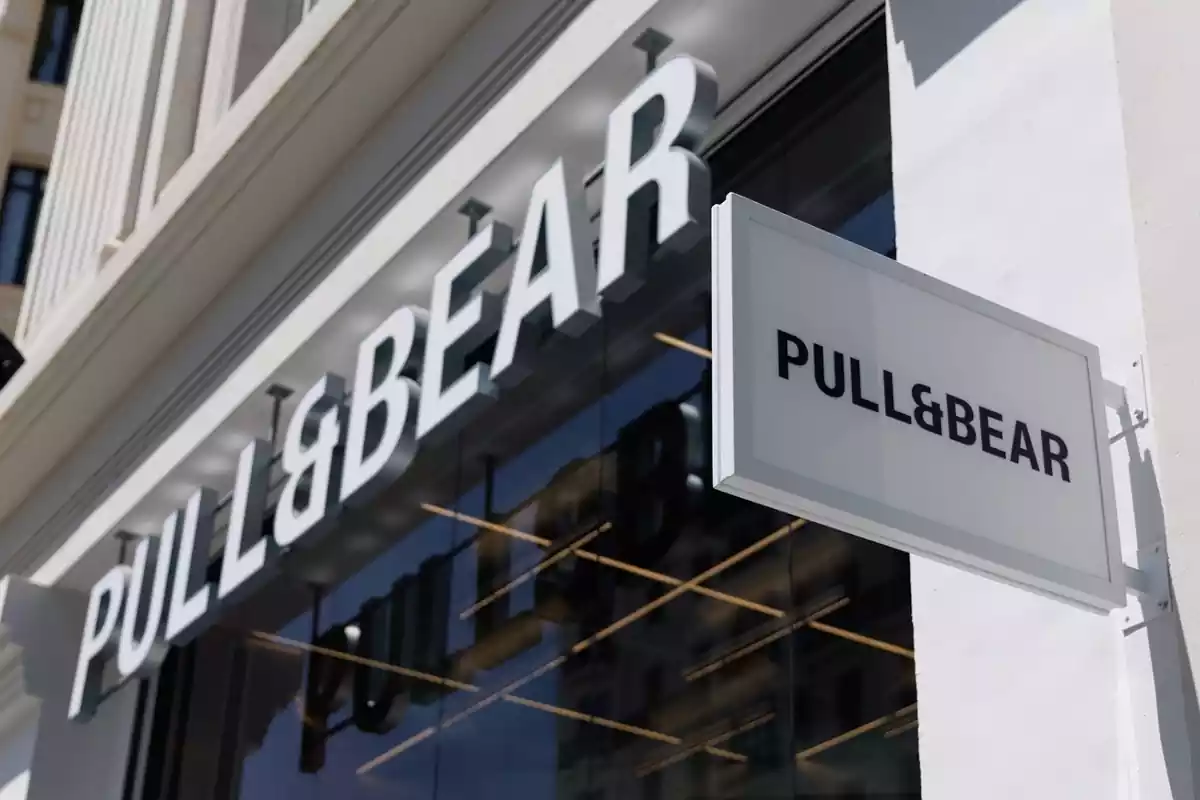 Exterior d'una botiga de Pull&Bear amb un rètol de grans dimensions i un cartell amb el logotip de la mateixa marca