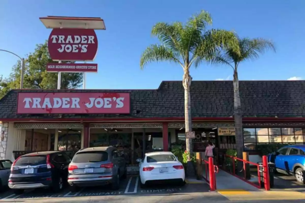 Fachada de una tienda Trader Joe's con autos estacionados al frente y dos palmeras junto a la entrada Fachada de una tienda Trader Joe's con autos estacionados al frente y dos palmeras junto a la entrada