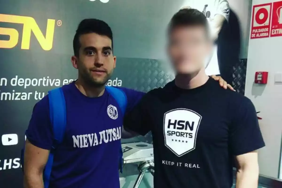 Dues persones posen juntes en un gimnàs, una porta una samarreta morada amb la inscripció Dues persones posen juntes en un gimnàs, una porta una samarreta morada amb la inscripció