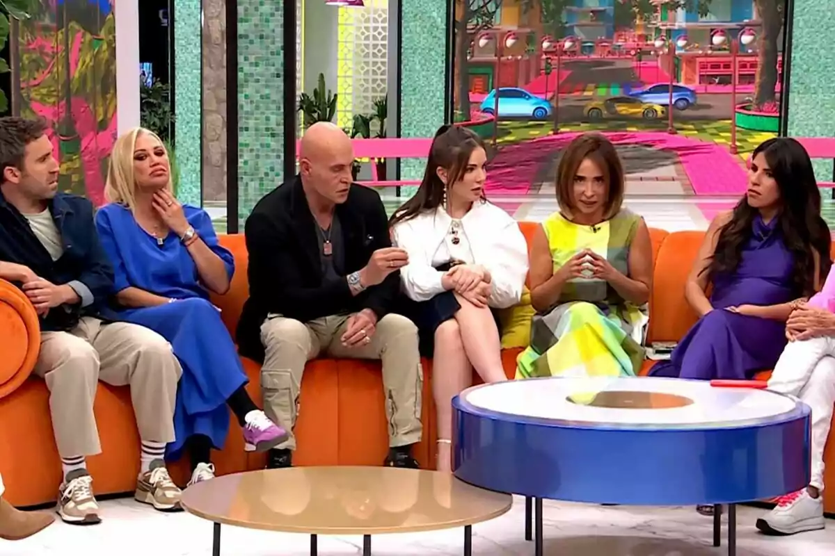 Un grup de persones format per Aitor Albizua, Belén Esteban, Kiko Matamoros, Inés Hernand, María Patiño i Isa Pantoja està assegut en un sofà de color taronja en un plató de televisió de La Família de la Tele, conversant i prestant atenció a la discussió.